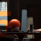 Owen Wilson's Agent Mobius in his TVA suit, sits across a table from Tom Hiddleston's Loki in his prison garb with a sphere-like TV in between them.